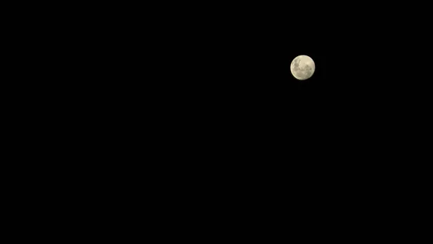 Lua cheia em cor de gelo em um céu completamente preto.