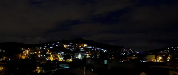 Luzes de casas à noite por todo horizonte montanhoso.